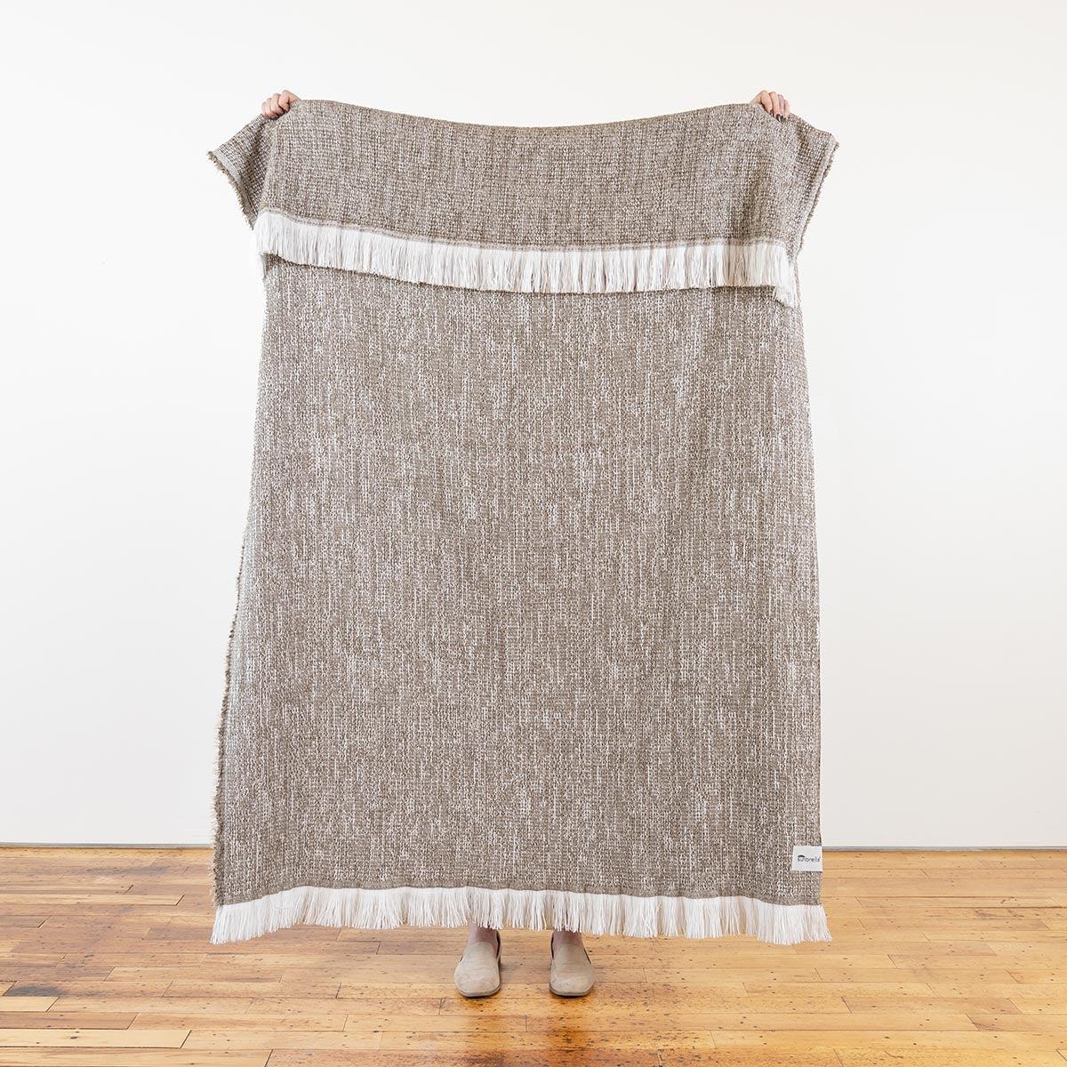 sunbrella-crosshatch-throw-latte-full-size-held-up-4_f6785971-8a8b-4526-a60e-6e31bcb276ba.jpg